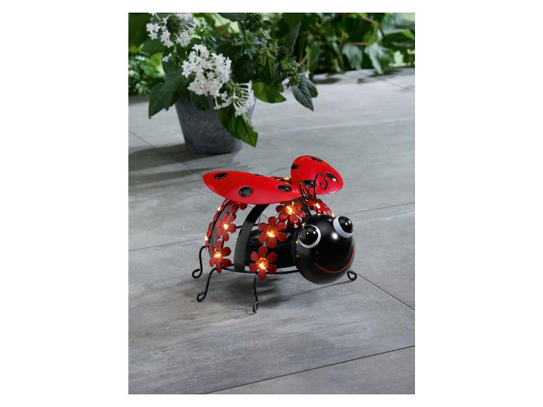 Metallene Lichterkette in Marienkäferform mit roten Blüten.