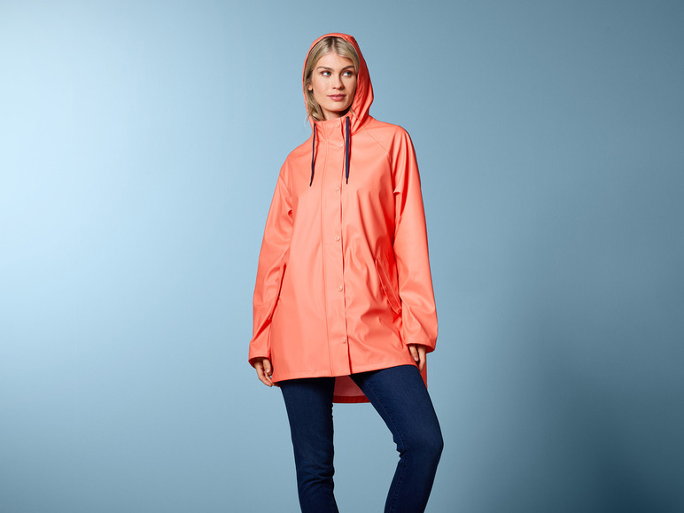Eine Frau trägt einen rosafarbenen Regenmantel mit Kapuze.
