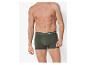 Mann in dunkelgrünen Boxershorts mit weißem Text am Bund.