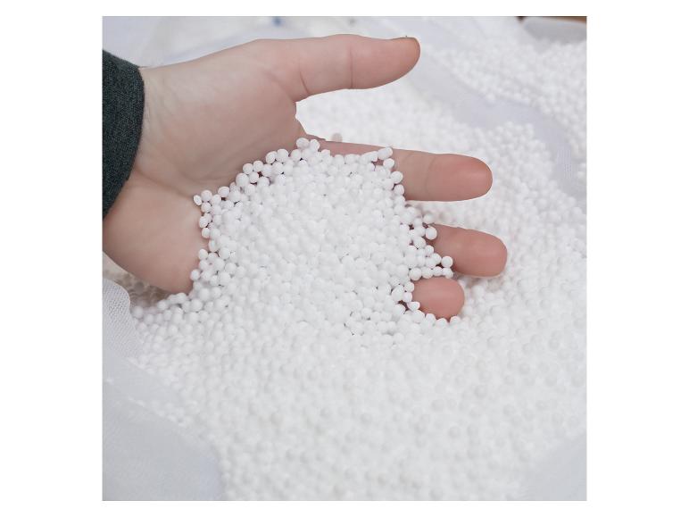 Hand hält weiße Styroporkugeln, verwendet für Füllungen oder Bastelarbeiten.