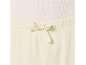 Detail eines cremefarbenen Oberteils und einer Hose mit Kordelzug.