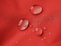 Wassertropfen auf einem roten, wasserdichten Stoff.