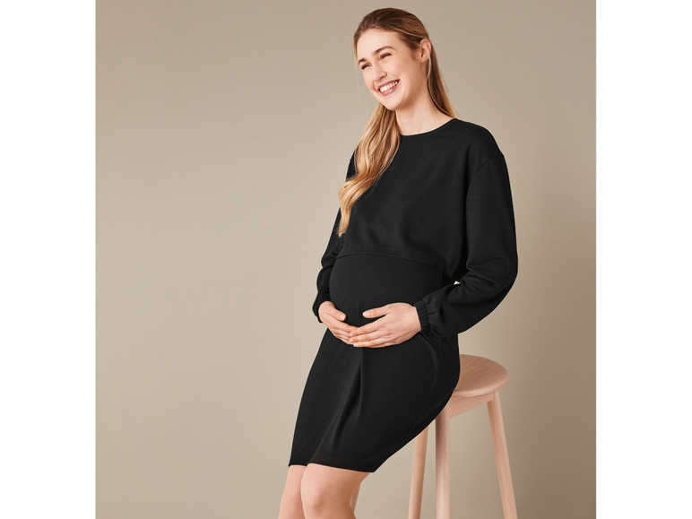 Schwangeres Model in einem schwarzen Umstands Kleid.