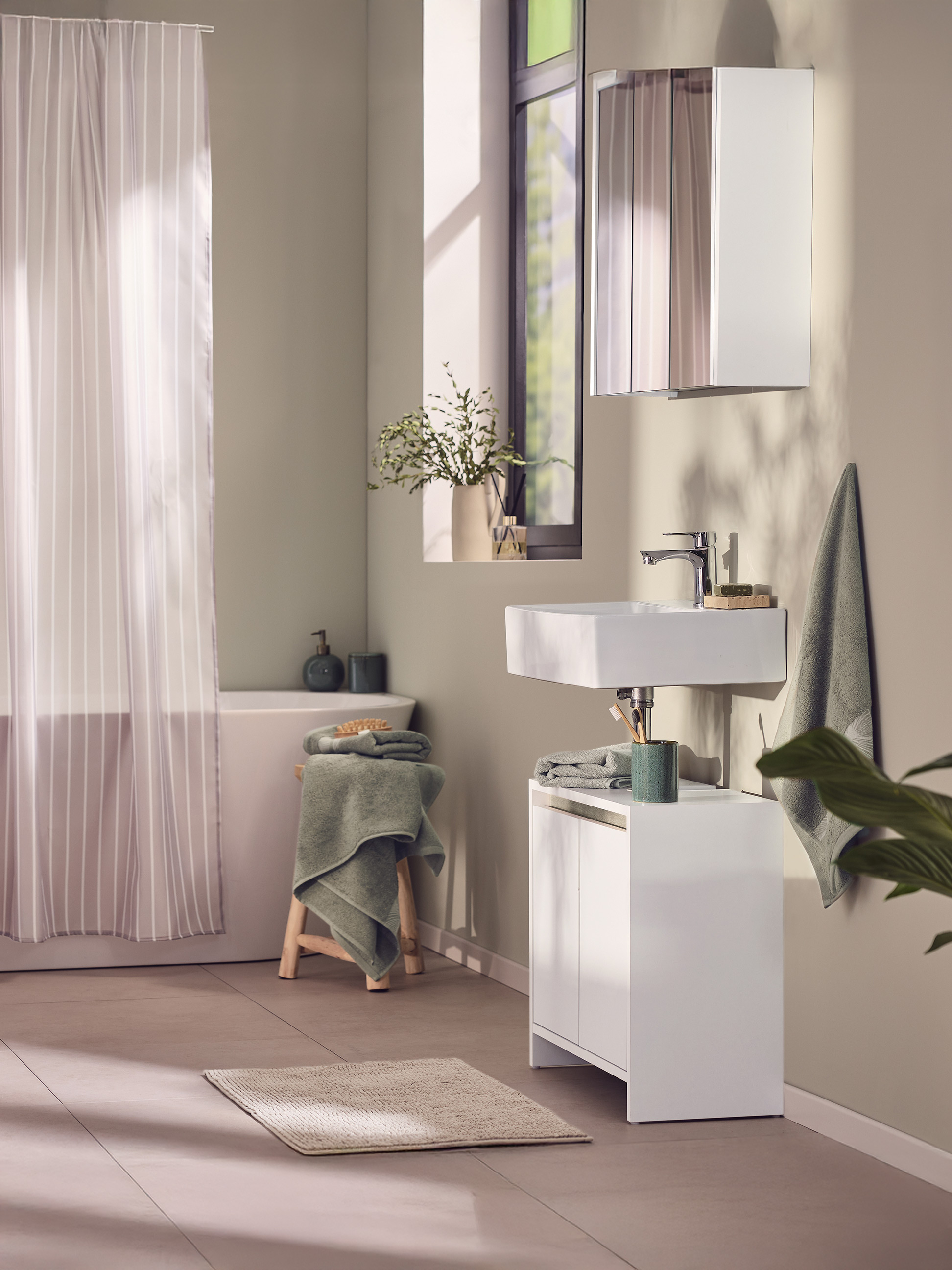 Modernes Badezimmer mit weißem Waschbecken, Waschtischunterschrank und gestreiftem Duschvorhang.