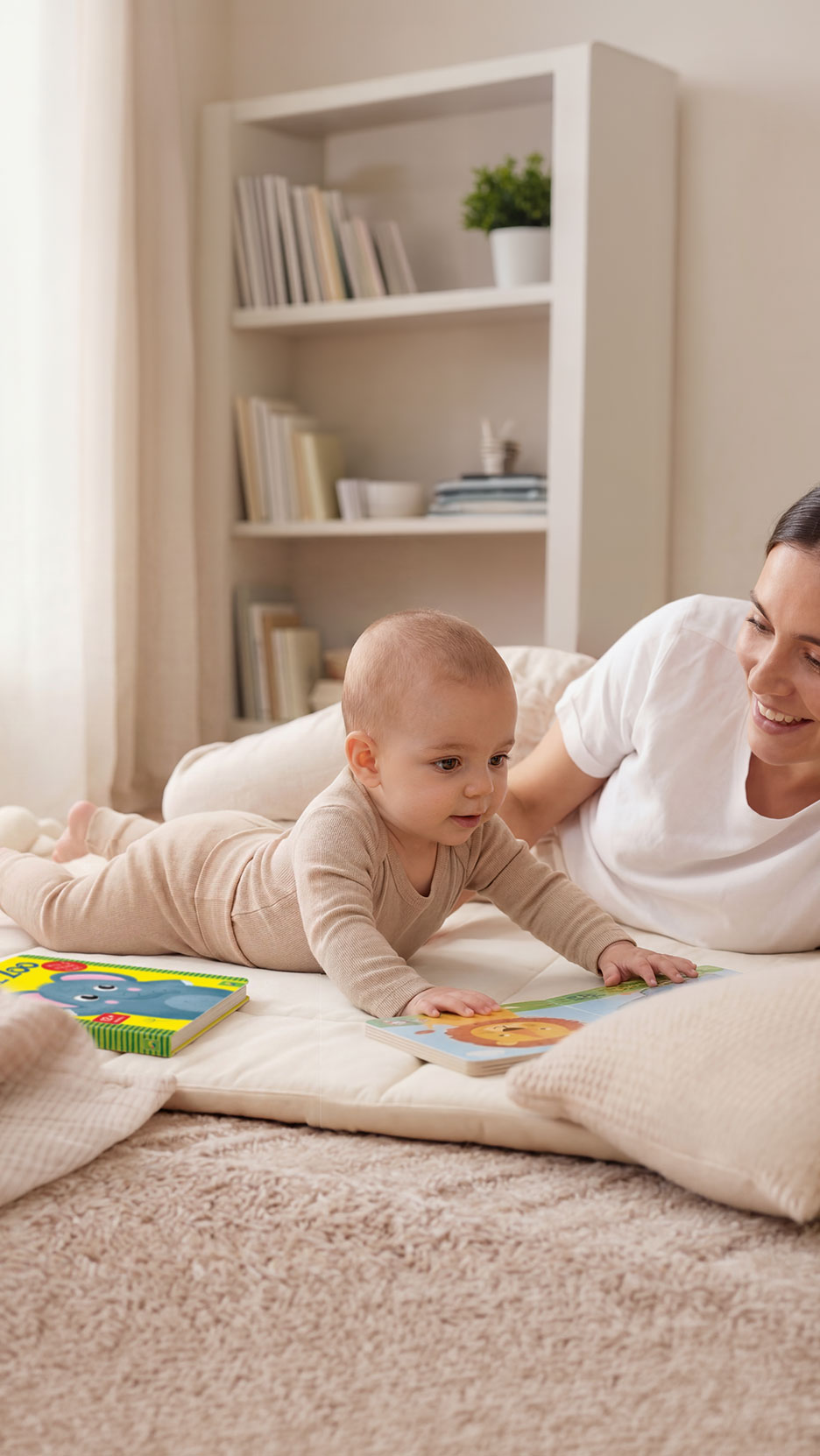 Baby und Mutter auf Matte mit Büchern, neben einem Bücherregal.
