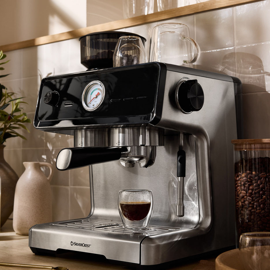 SilverCrest Espressomaschine aus Edelstahl mit einer Tasse Kaffee und Bohnen.