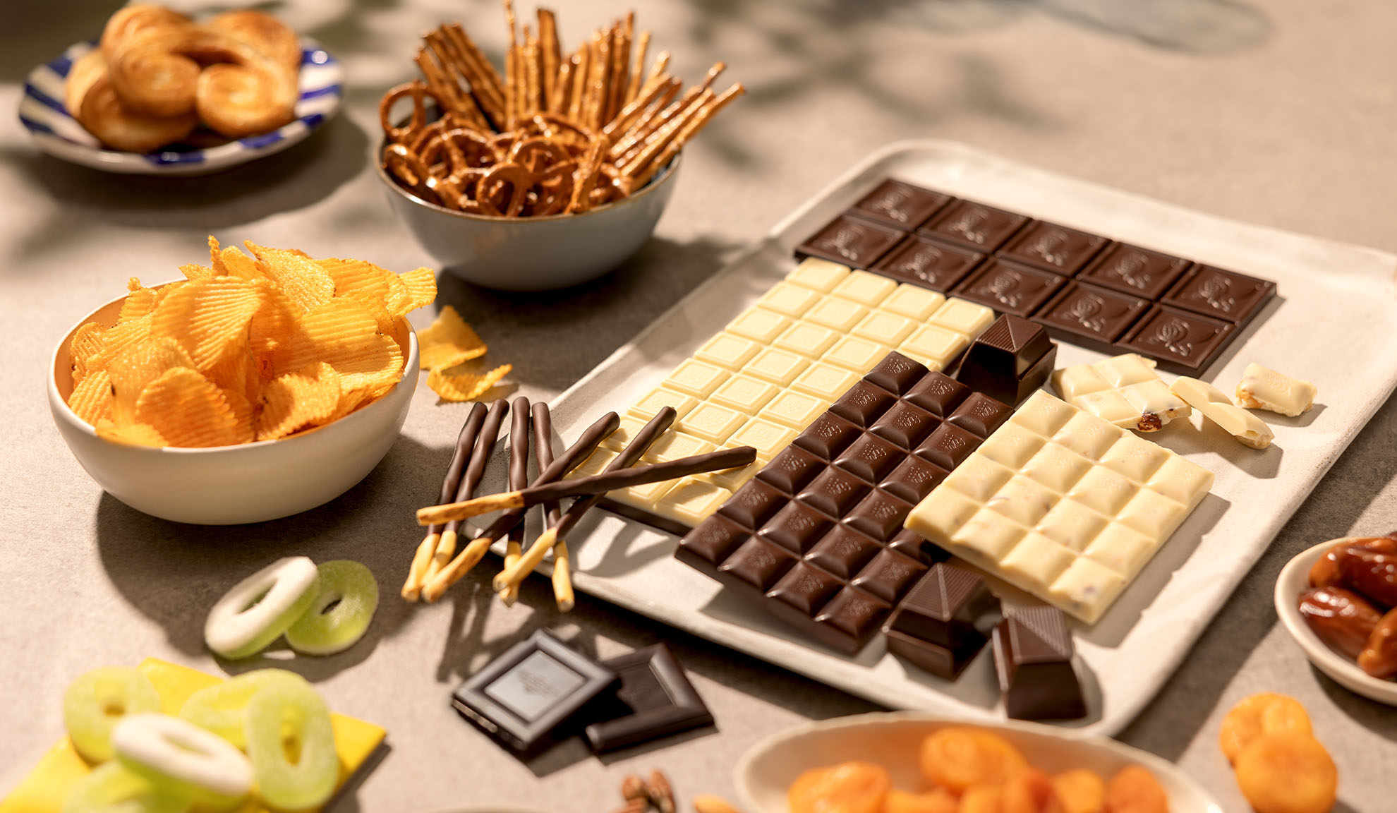 Eine Auswahl an Snacks wie Schokoriegel, Kartoffelchips, Brezeln und Süßigkeiten.