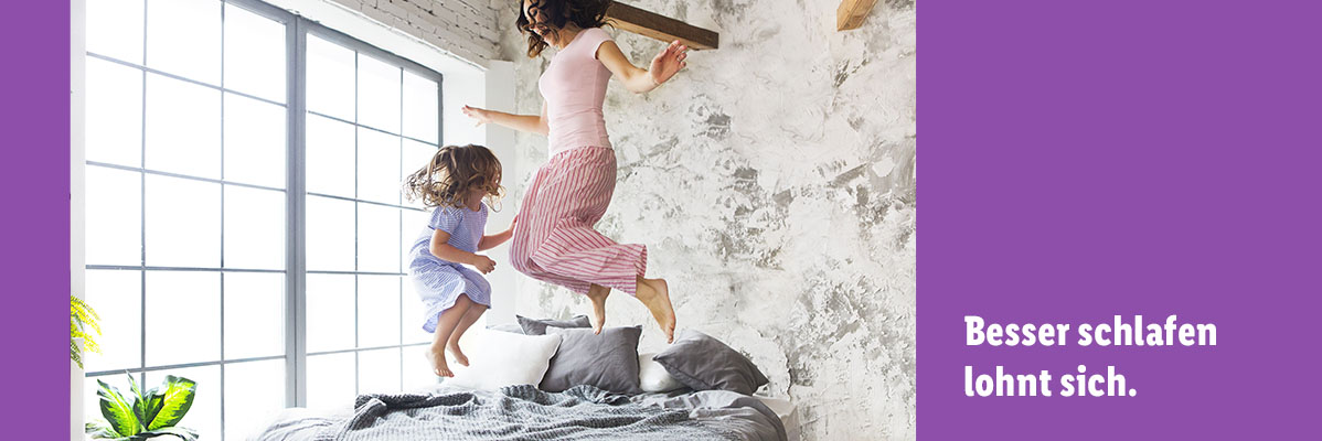 Mutter und Tochter springen auf dem Bett.