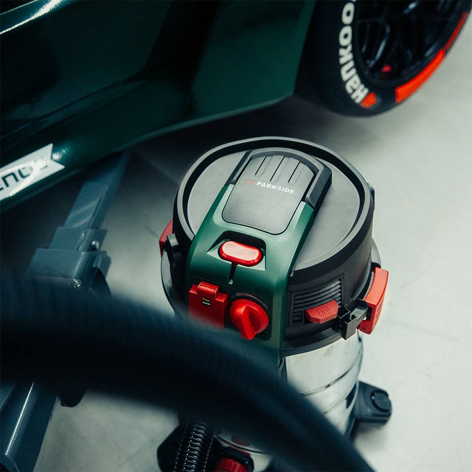 Industriestaubsauger mit roten und grünen Details, neben einem Sportwagen.