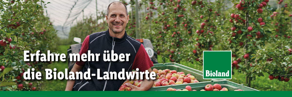 Erfahre mehr über die Bioland-Landwirte. Bioland-Landwirt lächelt vor seinen Apfelbäumen.
