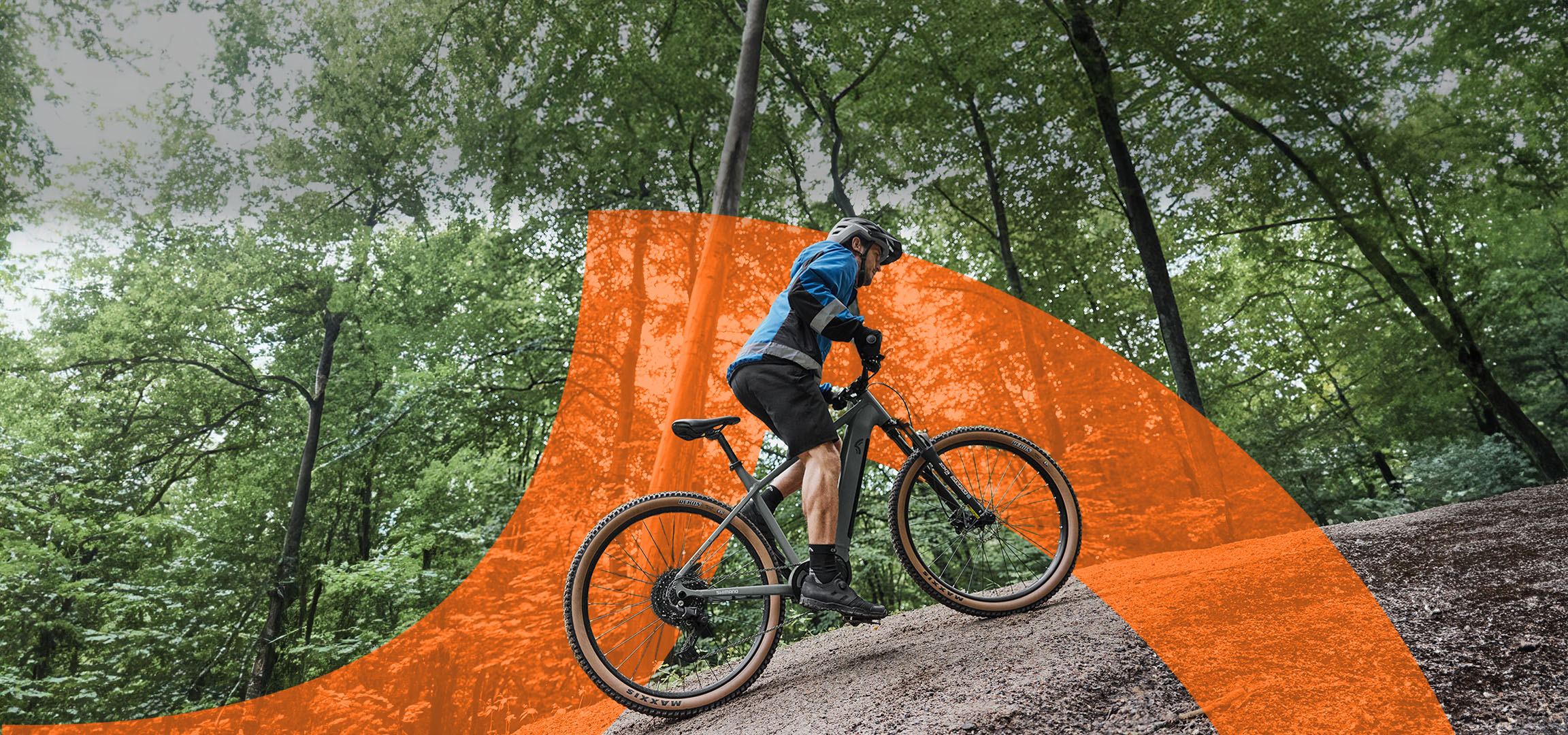 Mountainbiker in blauer Jacke auf einem Fahrrad im Wald, orangefarbene Überlagerung