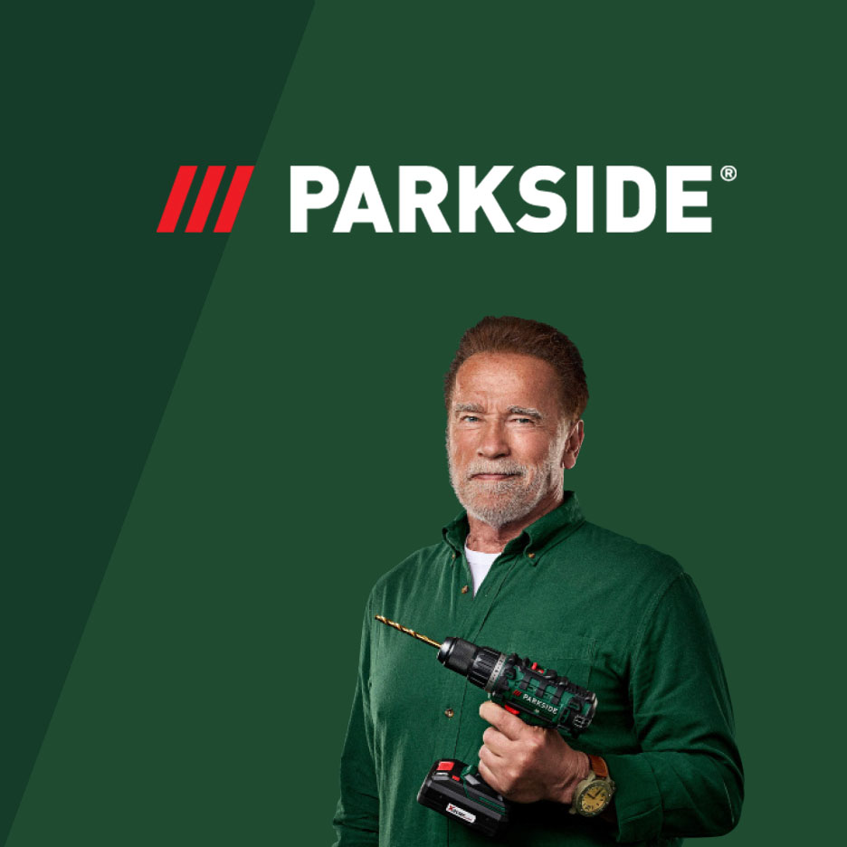 Arnold Schwarzenegger hält einen Parkside Akkuschrauber vor grünem Hintergrund.