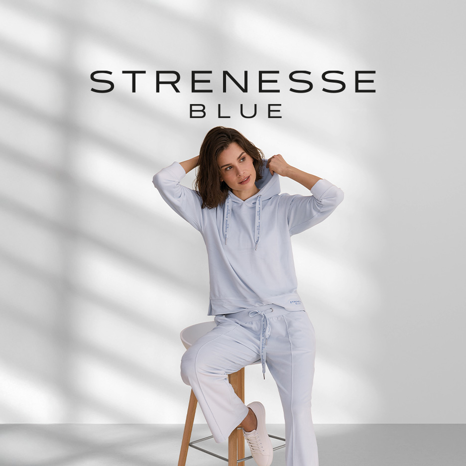 Frau in hellblauem Hoodie und Jogginghose auf einem Hocker sitzend.