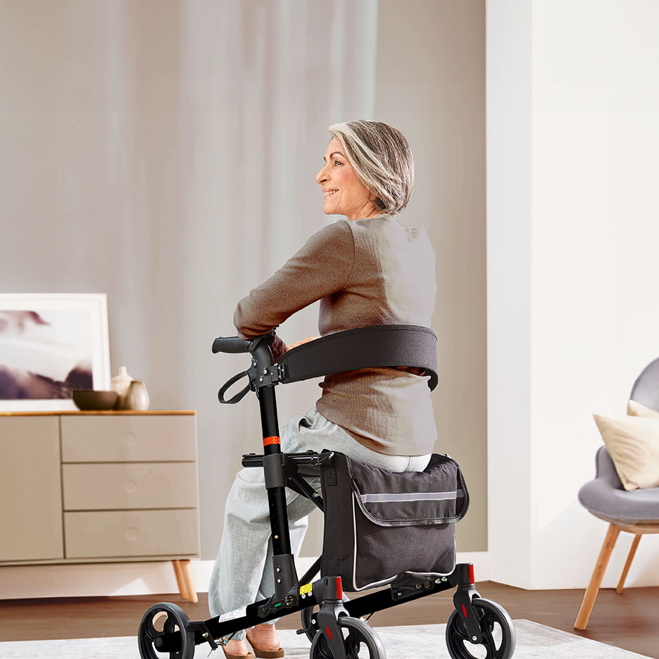 Ältere Frau sitzt lächelnd auf einem Rollator mit Tasche in einem Wohnzimmer.