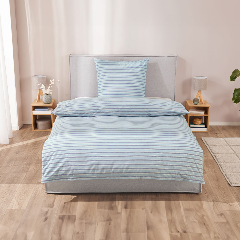 Schlafzimmer mit gestreifter Bettwäsche, Nachttischen und Lampen