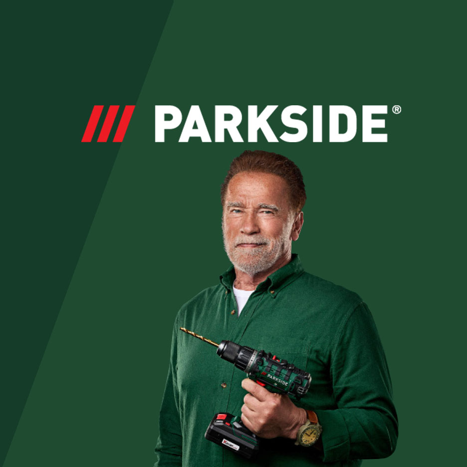 Arnold Schwarzenegger hält einen Parkside Akkuschrauber vor grünem Hintergrund.