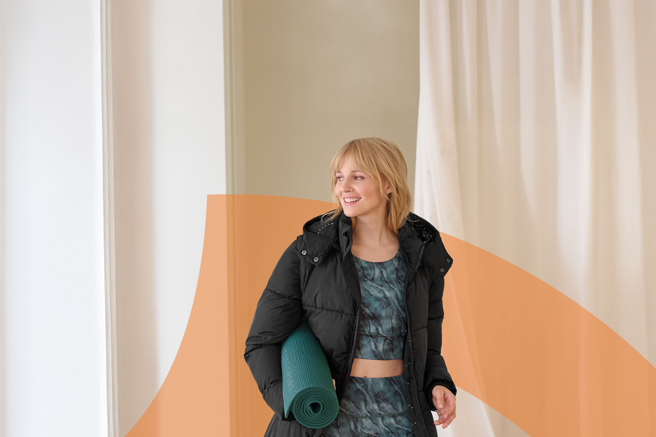 Frau in schwarzer Steppjacke und Sport-BH mit Yogamatte