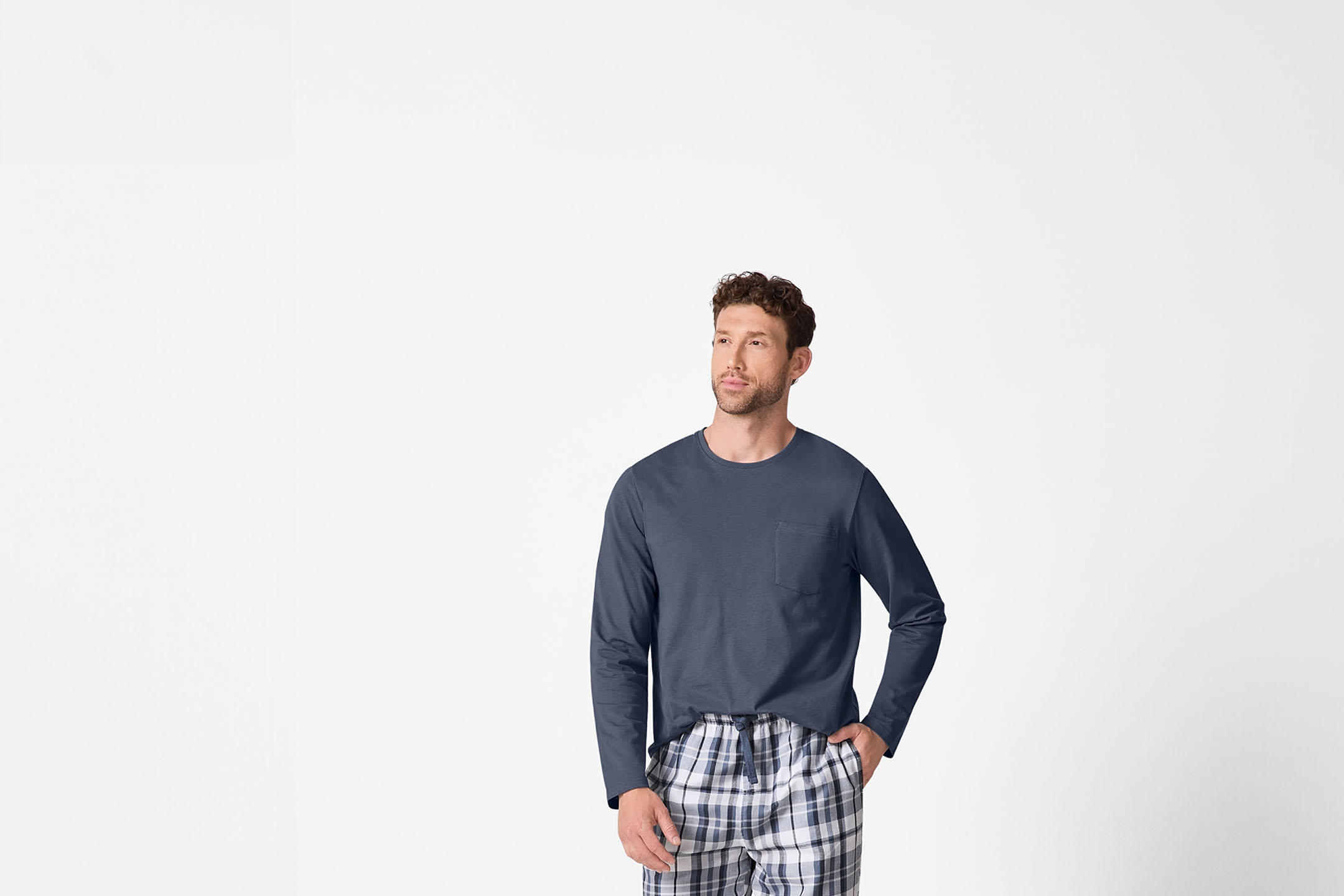 Mann in blauem Langarmshirt und karierter Pyjamahose