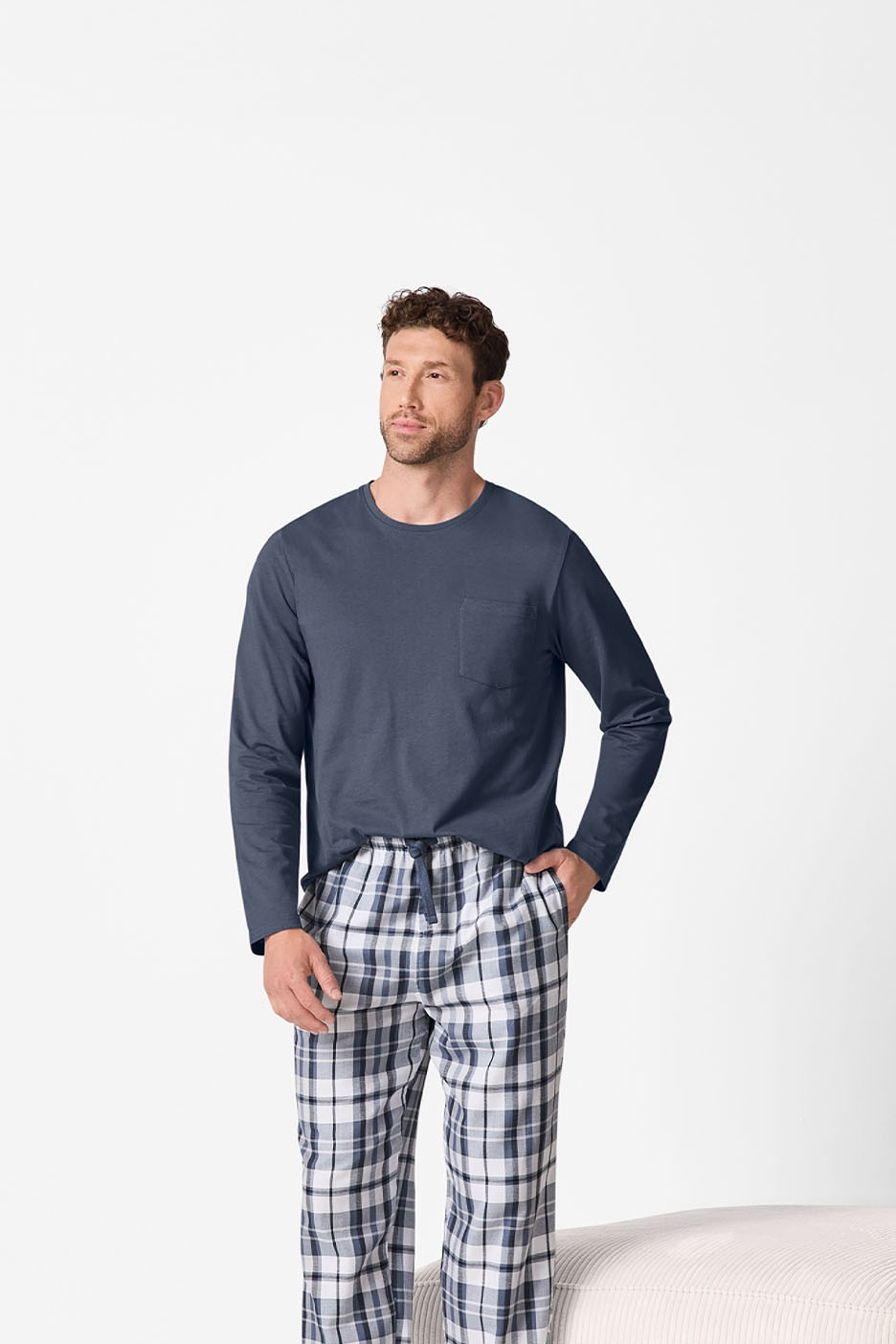 Mann in blauem Langarmshirt und karierter Pyjamahose