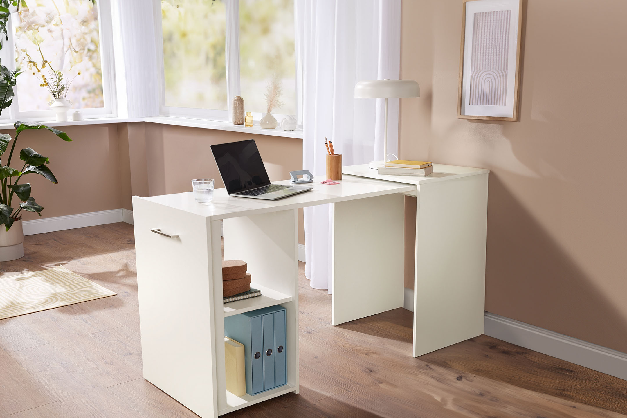 Weißer Eckschreibtisch mit Laptop und Büromaterialien in einem hellen Raum mit Fenster.