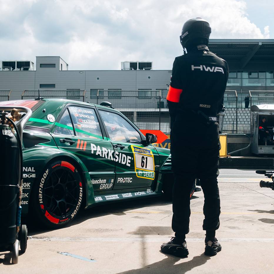 Grüner Rennwagen mit der Nummer 61 und ein Teammitglied in schwarzem Anzug.