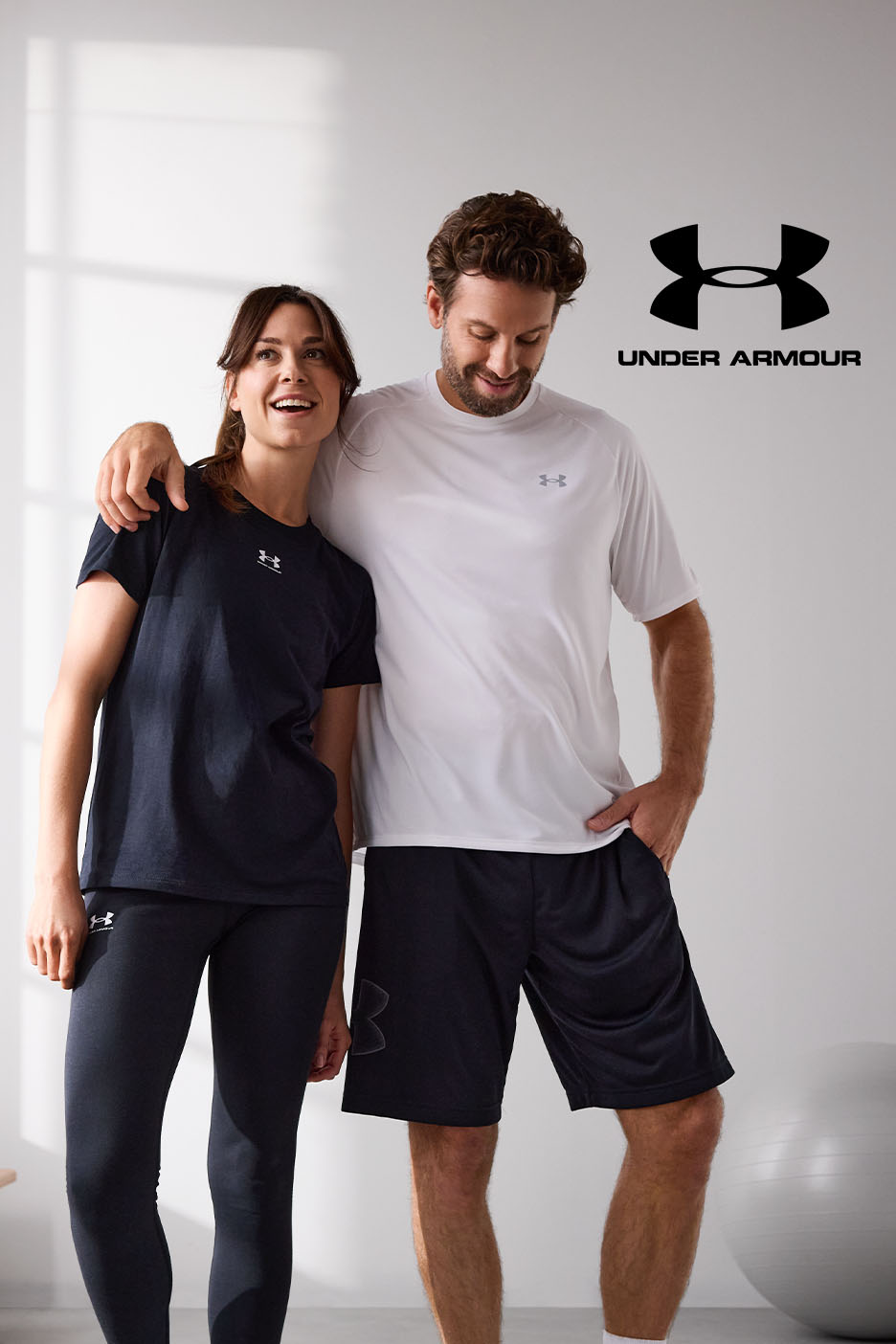 Ein Paar in Under Armour Sportbekleidung, sie trägt Leggings und ein T-Shirt, er Shorts und ein T-Shirt.