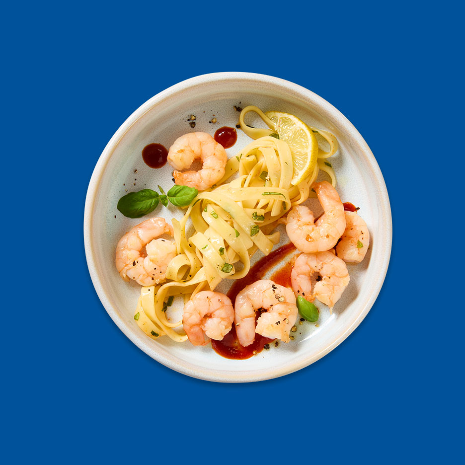 Garnelen und Bandnudeln mit Basilikum, Zitrone und Soße auf einem Teller