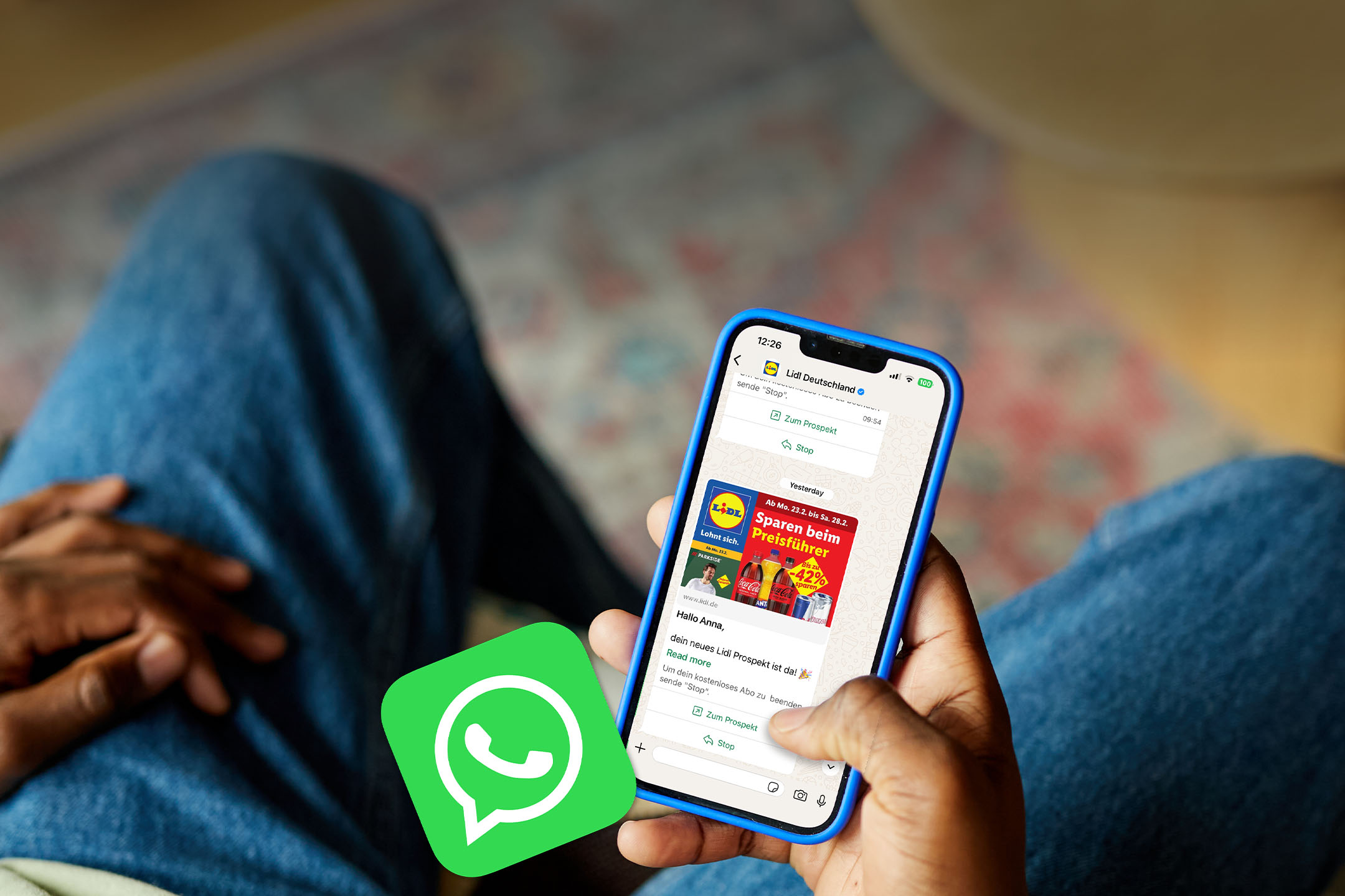 Eine Person hält ein Smartphone mit einer Nachricht, die ein Prospekt mit Angeboten für Getränke und andere Produkte zeigt.