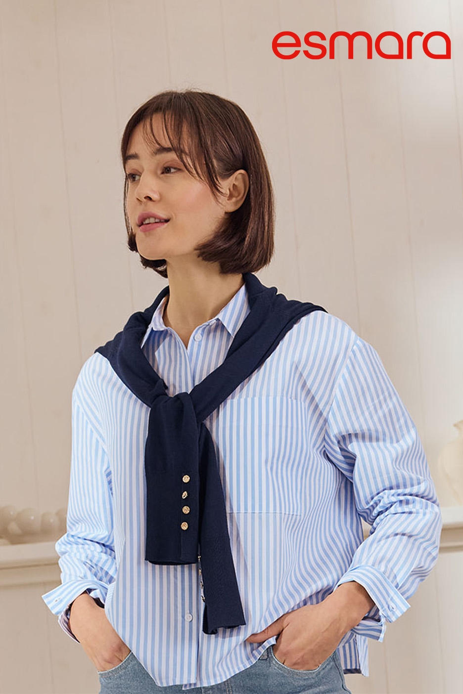 Frau in blau-weiß gestreiftem Hemd mit dunkelblauem Pullover um die Schultern