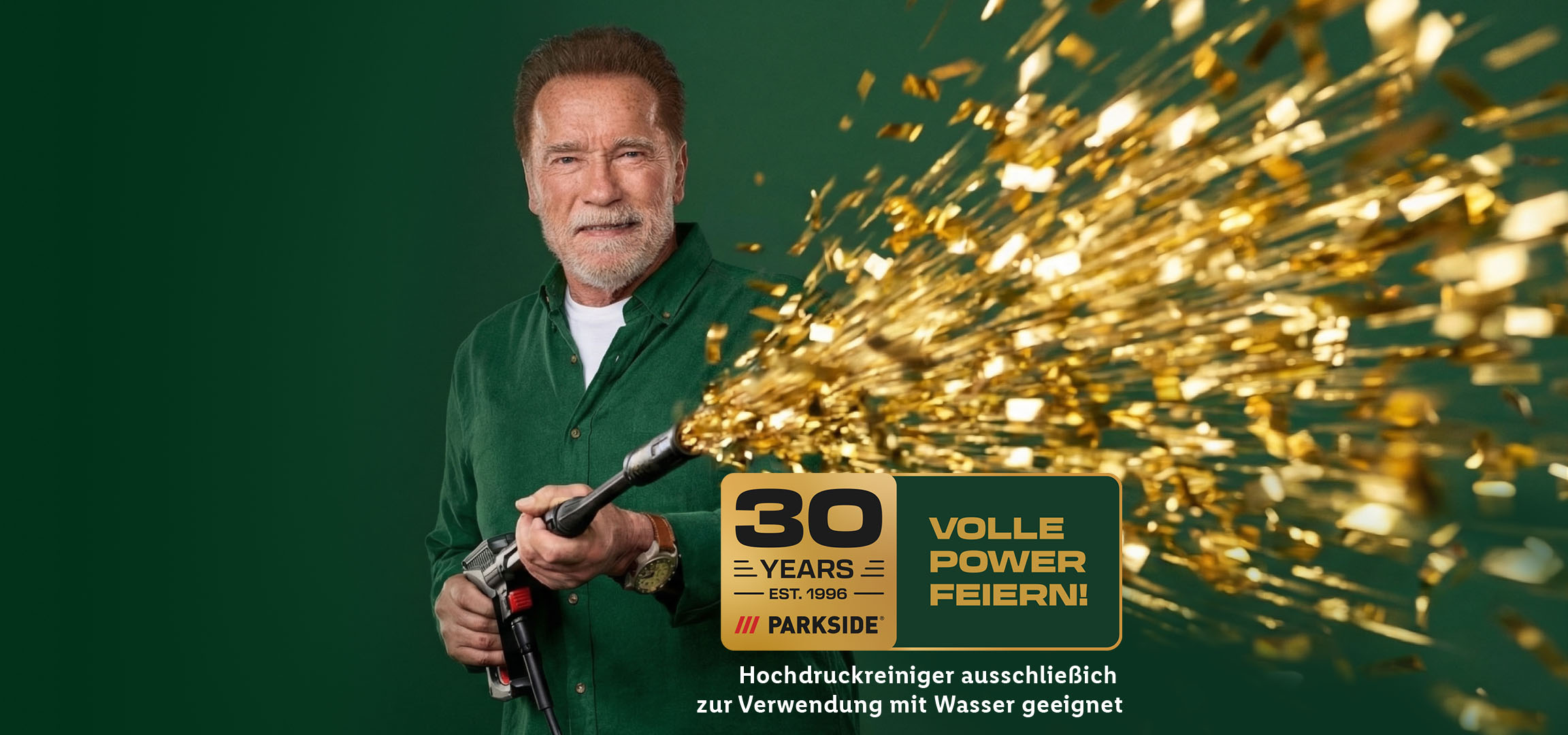 Ein Mann mit Bart hält einen Hochdruckreiniger, der goldenes Konfetti versprüht, mit dem Text '30 Jahre volle Power feiern!'.