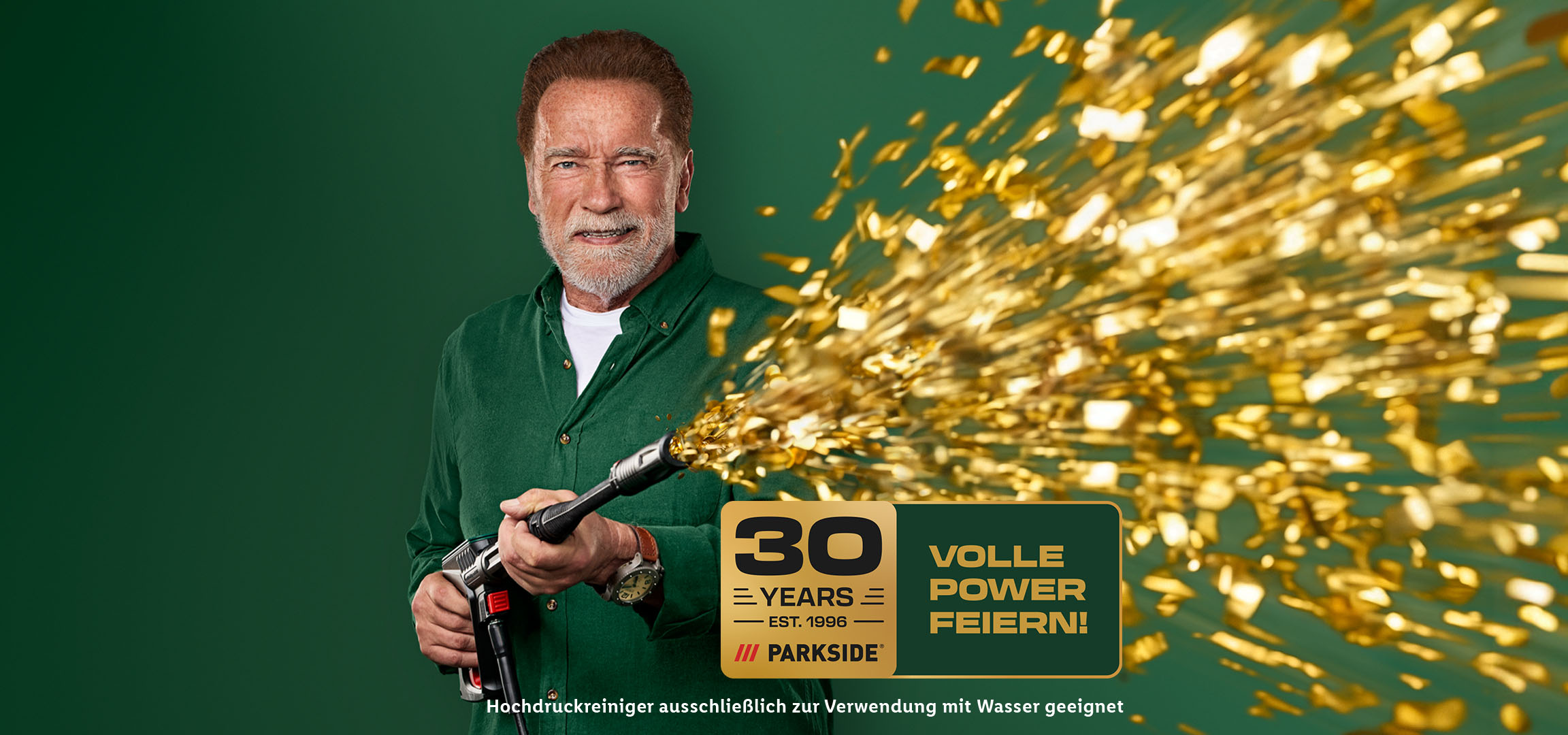 Arnold Schwarzenegger mit einem Hochdruckreiniger und dem Logo „30 Jahre Parkside“. Hochdruckreiniger ausschließlich zur Verwendung mit Wasser geeignet