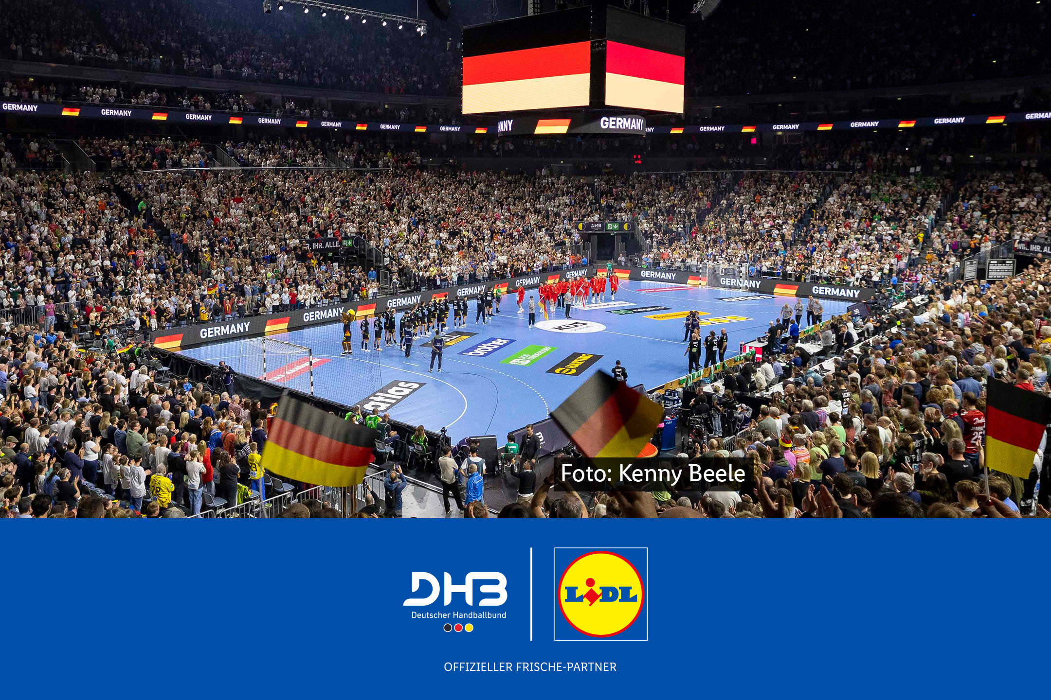 Ein vollbesetztes Handballstadion während eines Länderspiels mit Fans und Flaggen neben Logos von DHB und Lidl. Lidl ist offizieller Frische-Partner. Foto: Kenny Beele