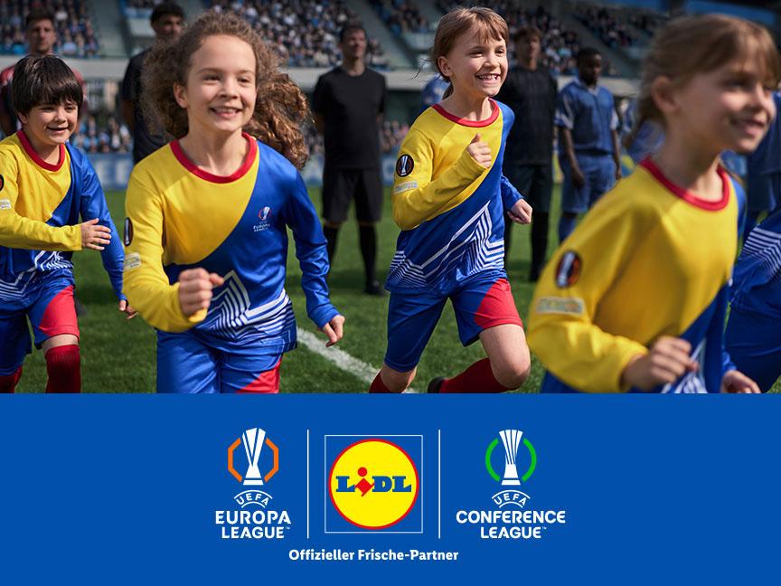 Fröhliche Kinder in Fußballtrikots laufen auf das Spielfeld ein über Logos für UEFA Europa League und UEFA Conference League. Lidl ist Offizieller Frische-Partner.