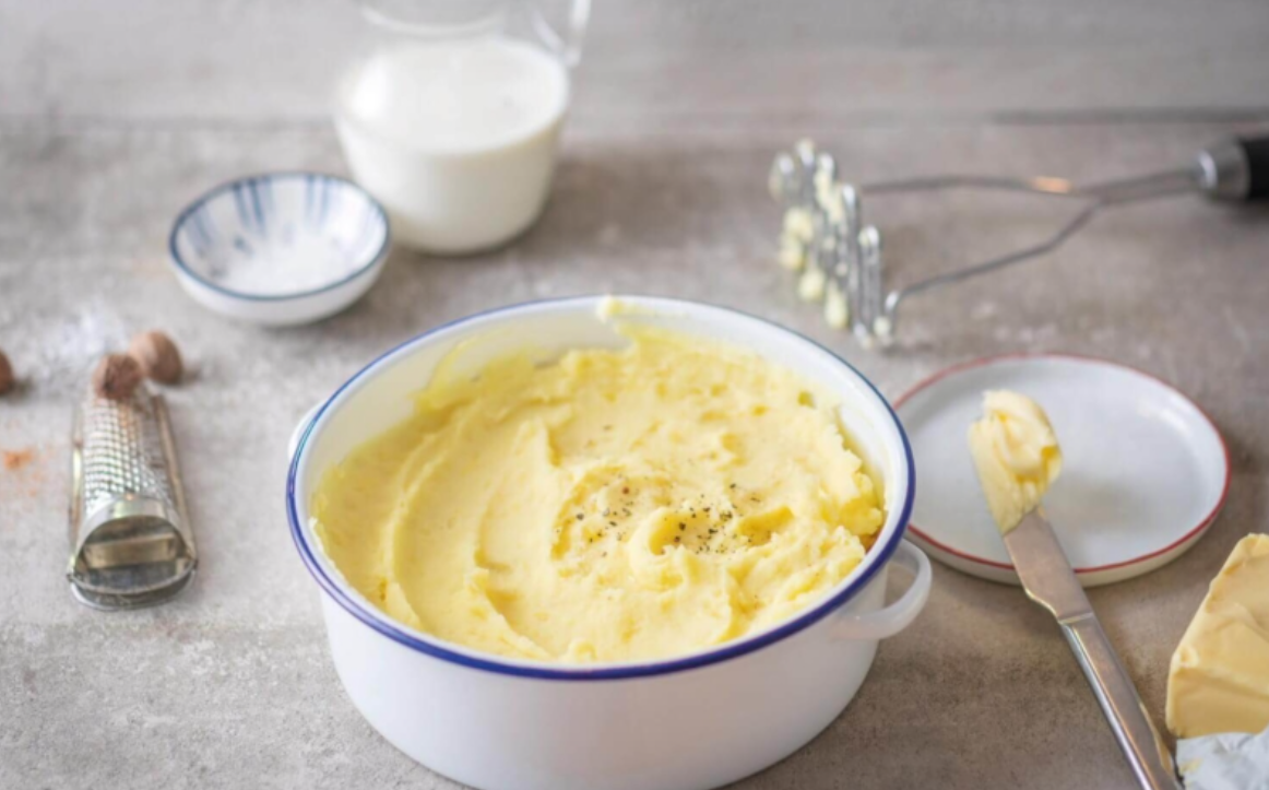 Cremiges Kartoffelpüree in einer Schüssel mit Butter, Milch und Gewürzen.