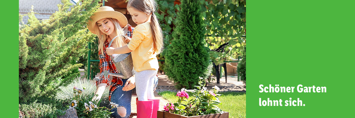Mutter und Tochter gießen Blumen und Sträucher im Garten.