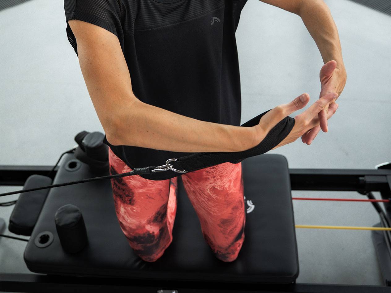 Frau trainiert mit Widerstandsbändern an einem Pilates-Gerät.