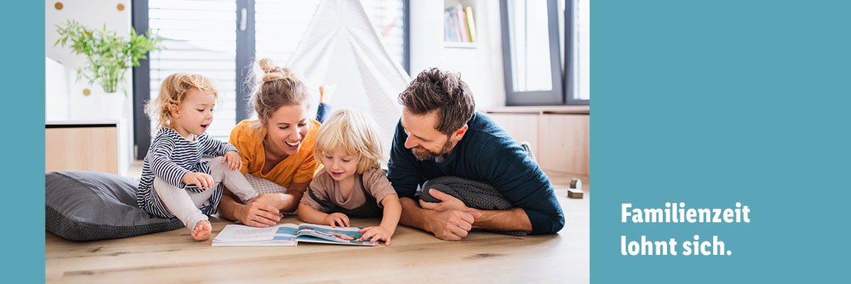 Familie liest gemeinsam ein Buch auf dem Boden.