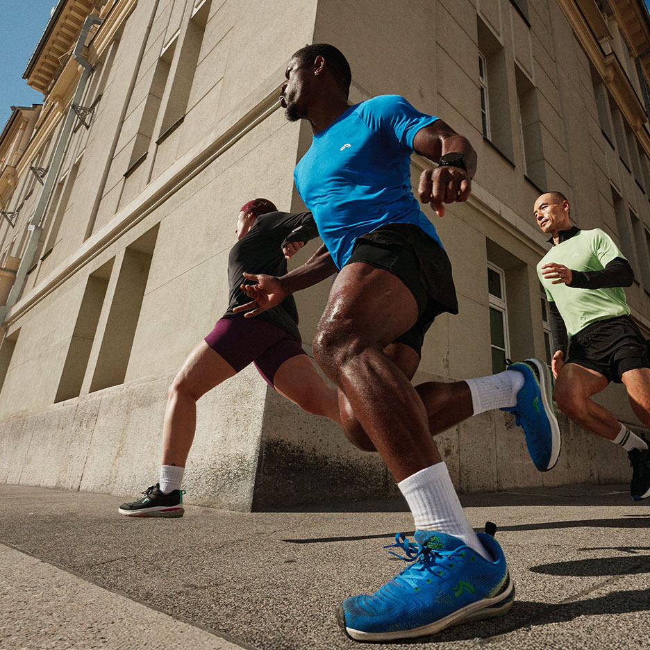 Drei Personen laufen in Sportkleidung und Laufschuhen die Straße entlang.
