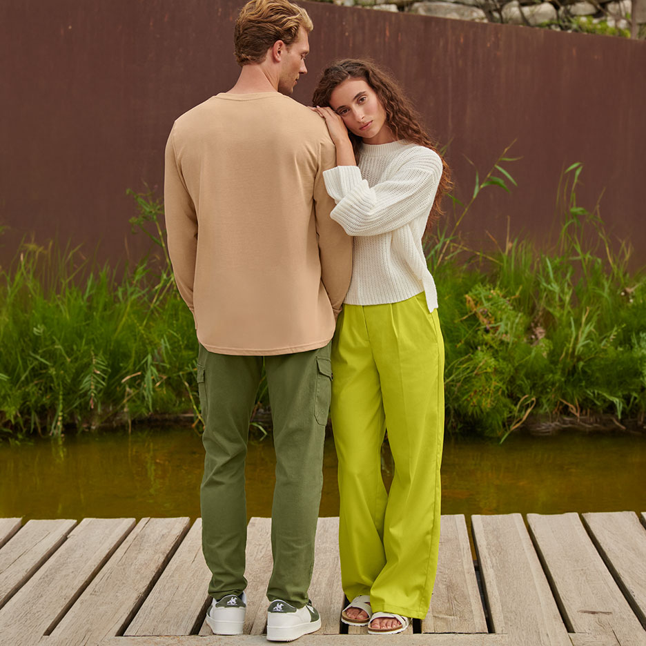 Mann in beigem Langarmshirt und grüner Cargohose, Frau in weißem Pullover und limettengrüner Hose.