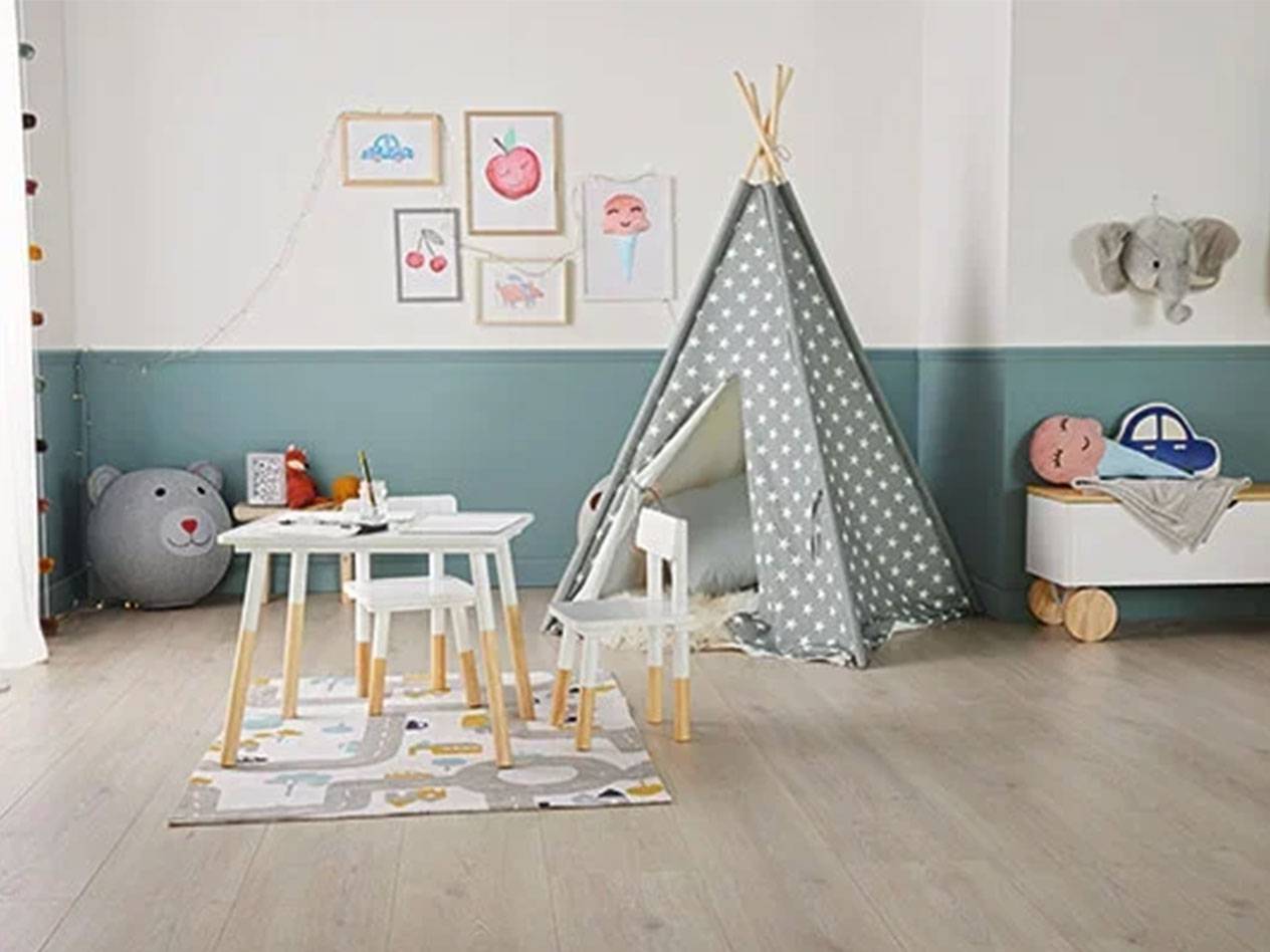 Kinderzimmer mit Tipi-Zelt, Tisch und Stühlen, Spielzeugkiste und Bildern an der Wand.