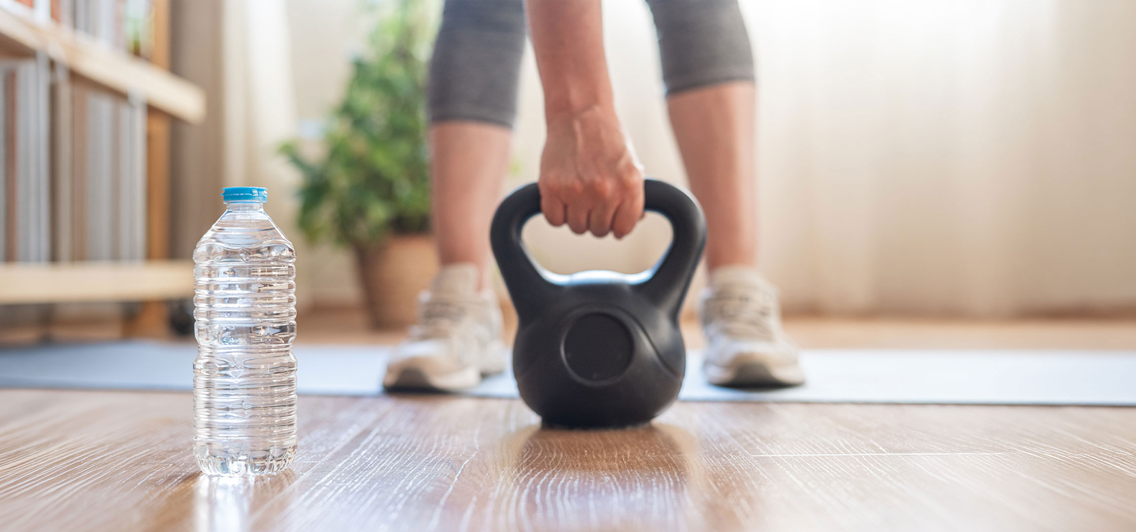 AI-generiert: Frau bereitet sich auf das Training mit einer Kettlebell und einer Wasserflasche auf einer Yogamatte vor.