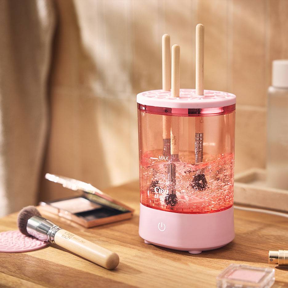Rosa Make-up-Pinselreiniger mit Pinseln in schäumendem Wasser.