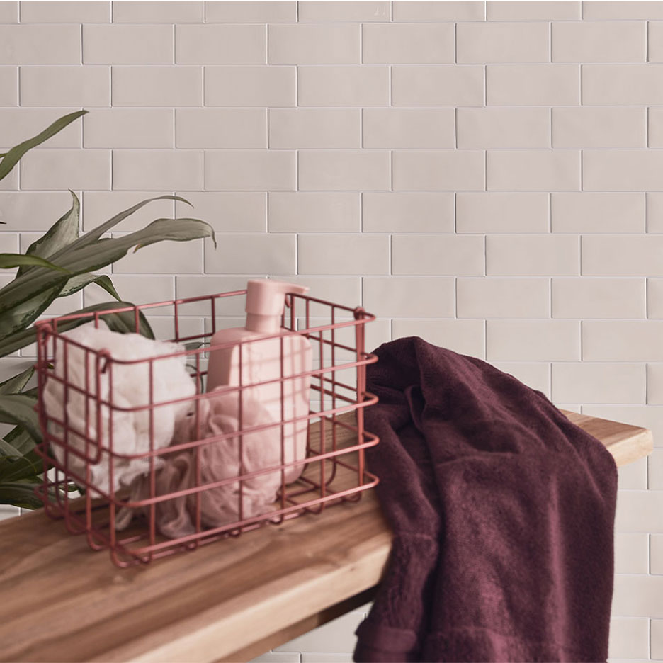 Badezimmer-Dekor mit weißen Fliesen, Holzbank, Korb mit Seife und Handtüchern.