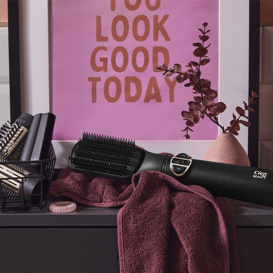 Cien Beauty Haarglättungsbürste auf einem Handtuch, mit Haarzubehör und einem Poster.