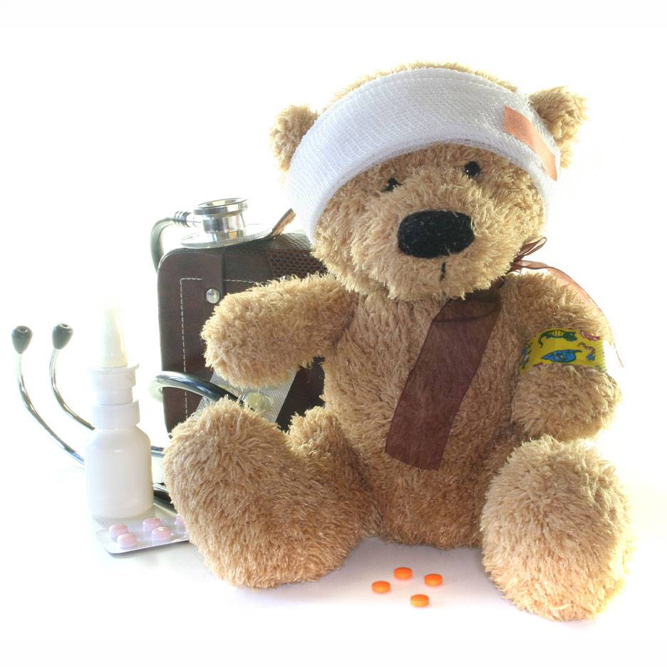Verletzter Teddybär mit Kopfverband, Arzttasche, Stethoskop und Medikamenten.