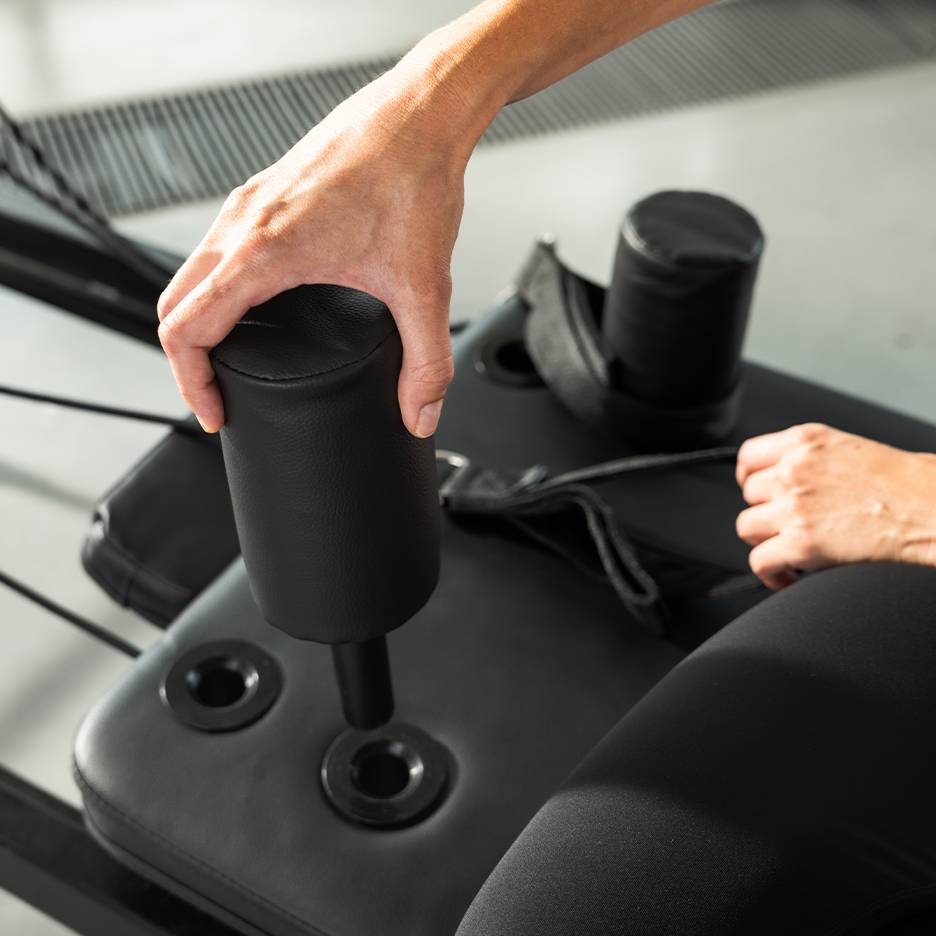 Person stellt ein schwarzes gepolstertes Trainingsgerät ein.