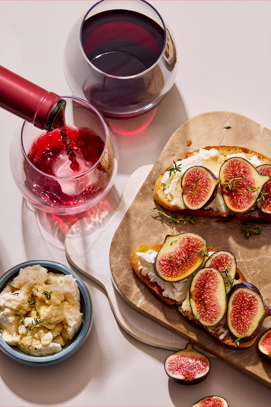 Rotwein wird in ein Glas gegossen, daneben Feigen-Crostini mit Frischkäse und Honig.