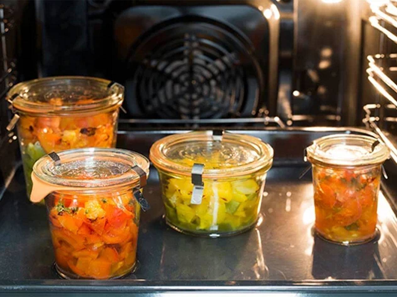 Vier Gläser mit bunten Gemüsestücken in einem Ofen