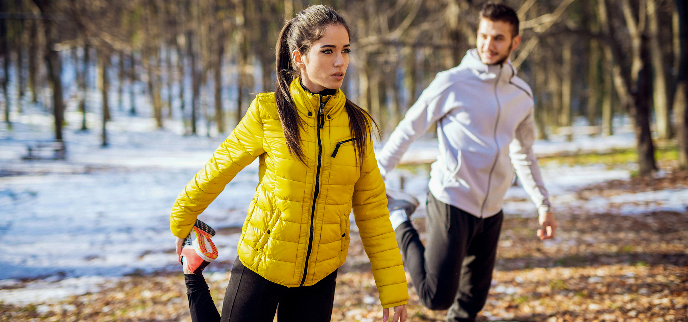 Zwei Personen in Winter-Sportkleidung, eine Frau in gelber Jacke und ein Mann in weißer Jacke.