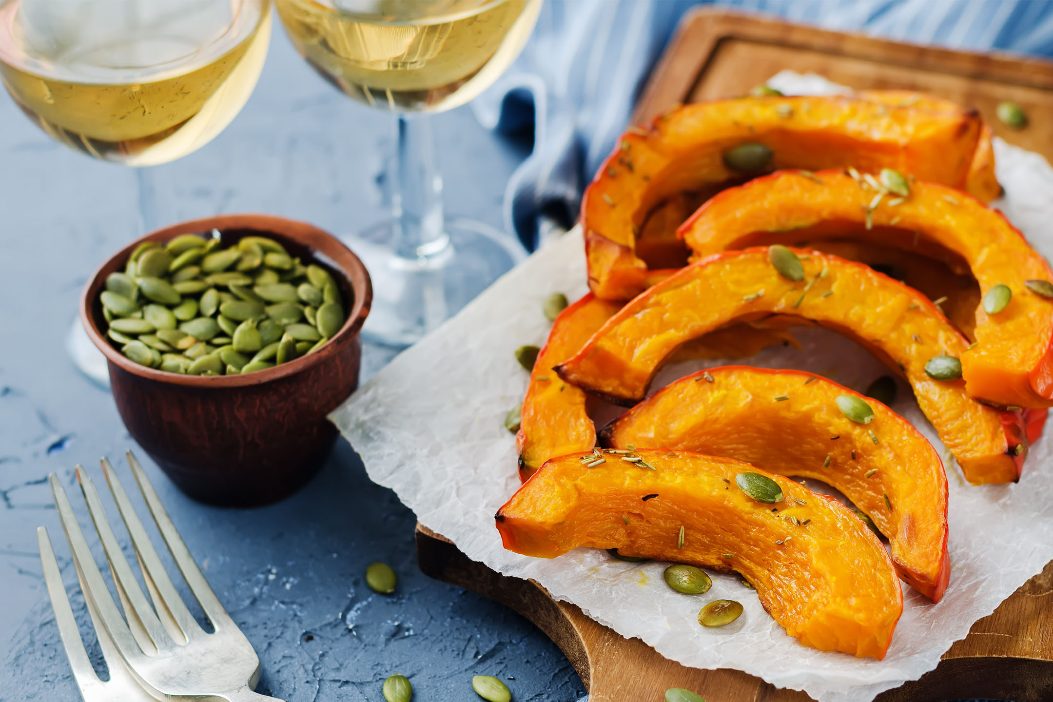 Geröstete Kürbisspalten mit Kürbiskernen und Rosmarin, serviert mit Weißwein.